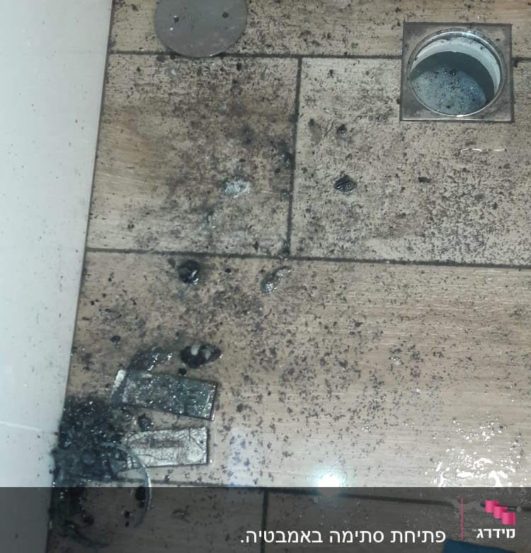 רצפה מלוכלכת עם פתח ניקוז פתוח ומכסה מתכת